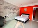 Modern bedroom with marble accent wall and bright orange feature wall