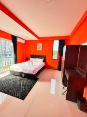 Modern bedroom with orange walls, large bed, and city view