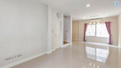 Spacious living room with large window and curtains, light fixtures, and polished floor