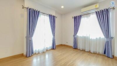 A well-lit empty bedroom with wooden flooring and purple curtains