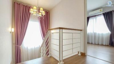 Elegant staircase landing with chandelier and curtains