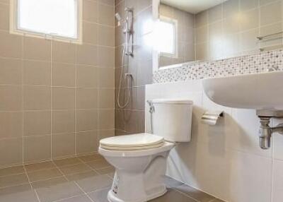 Modern bathroom with tiled walls and floor, shower, toilet, and sink