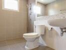 Modern bathroom with tiled walls and floor, shower, toilet, and sink