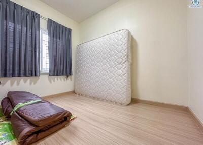 Empty bedroom with a mattress leaning against the wall and folded beddings on the floor