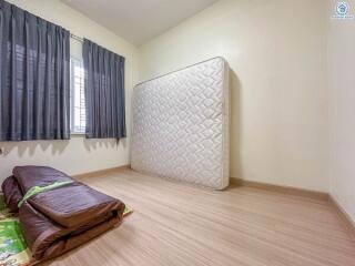 Empty bedroom with a mattress leaning against the wall and folded beddings on the floor