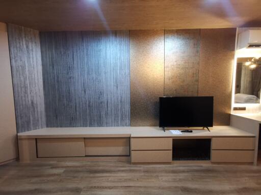 Modern living room with a wall-mounted TV and wooden flooring