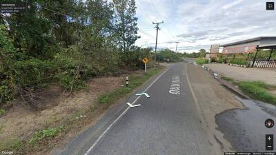 Rural road with foliage along the side and a partly cloudy sky