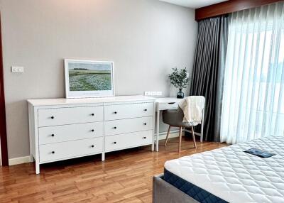 Modern bedroom with wooden flooring, white dresser, and bed