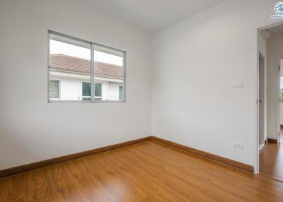 Empty bedroom with large window and wooden floor