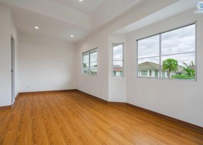 Bright empty bedroom with wooden floor and multiple windows