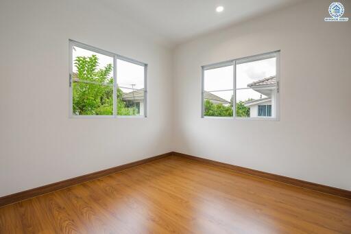 Spacious empty bedroom with wooden flooring and two large windows