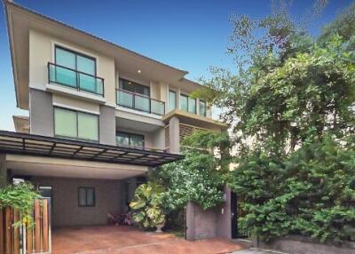 Modern multi-story house with a carport and lush greenery