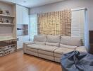 Cozy living room with a couch, wall-mounted shelves, and window blinds