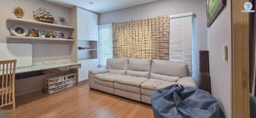 Cozy living room with a couch, wall-mounted shelves, and window blinds