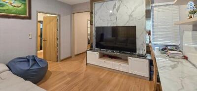 Living room with modern decor, featuring a TV, a bean bag, and wooden flooring