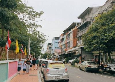 Street view of residential area with parked cars and pedestrians