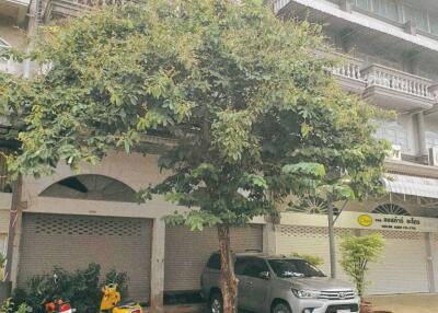 Front view of a multi-story residential building with street parking and a tree in front