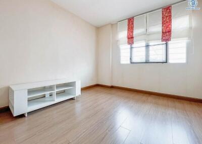 Empty bedroom with a small white TV stand and large window