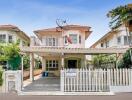 Front view of a residential house with a white fence and carport