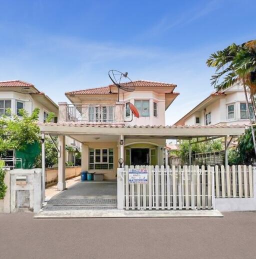 Front view of a residential house with a white fence and carport