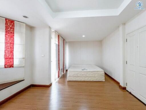 a bright and spacious bedroom with wooden flooring and simple decor