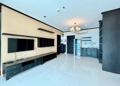 Modern living area with wall-mounted TV and open kitchen