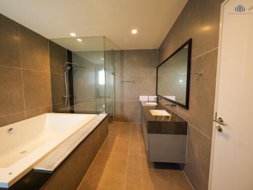 Modern bathroom with large bathtub, glass-enclosed shower, and wide vanity mirror