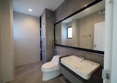 Modern bathroom with shower, toilet, and large mirror