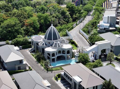 Aerial view of an elegant building with a dome and surrounding landscape