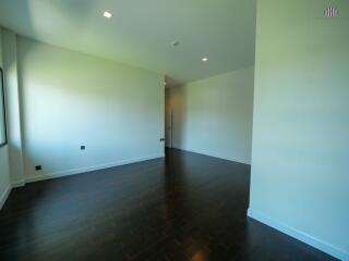 spacious living room with dark hardwood floors and white walls