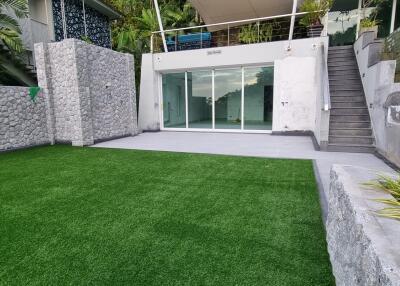 Modern outdoor area with glass doors, stairs, and artificial grass