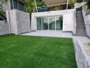 Modern outdoor area with glass doors, stairs, and artificial grass