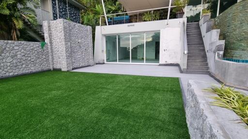 Modern outdoor area with glass doors, stairs, and artificial grass