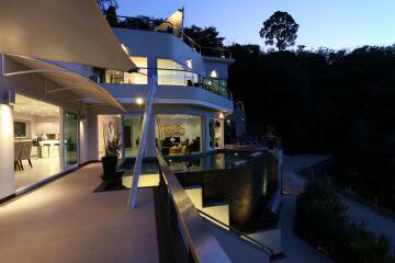 Modern multi-story house with glass balconies and outdoor pool at twilight