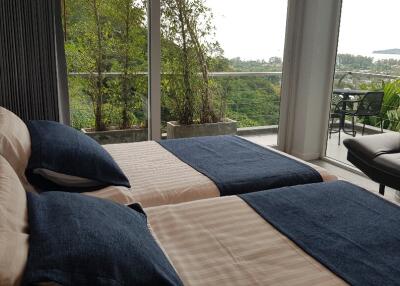 Modern bedroom with twin beds and balcony with scenic view