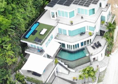 Aerial view of a modern multi-story house with solar panels and multiple balconies