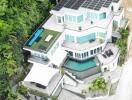 Aerial view of a modern multi-story house with solar panels and multiple balconies