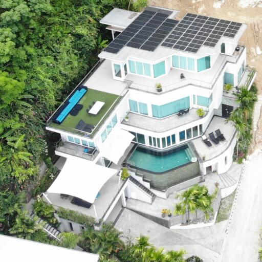 Aerial view of a modern multi-story house with solar panels and multiple balconies