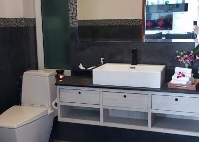Modern bathroom with a large mirror, sink, and toilet