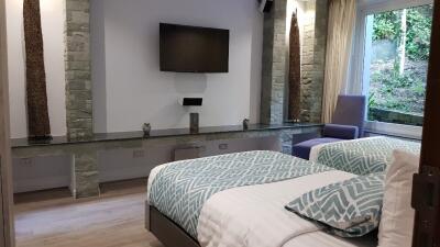 Bedroom with twin beds, a wall-mounted TV, and large window