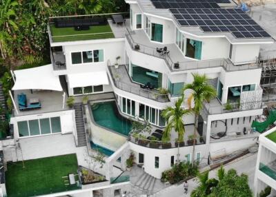 Modern multi-story house with rooftop solar panels and lush greenery