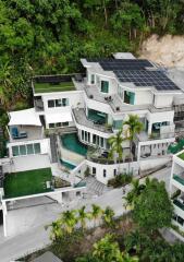 Modern multi-story house with rooftop solar panels and lush greenery