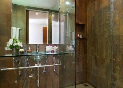 Modern bathroom with glass sink, large mirror, and tiled walls