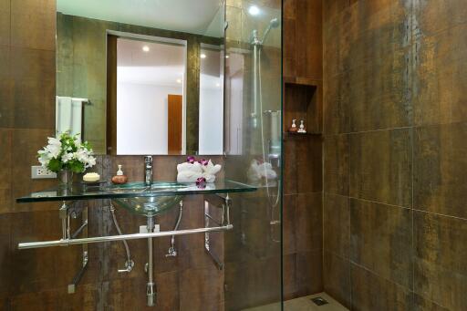 Modern bathroom with glass sink, large mirror, and tiled walls