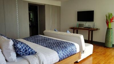 Modern bedroom with a bed, couch, wall-mounted TV, and decorative elements