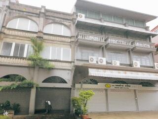 Exterior view of a multi-story residential building with air conditioning units and balcony