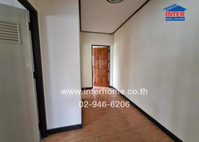 Hallway with tiled floor and wooden door at the end