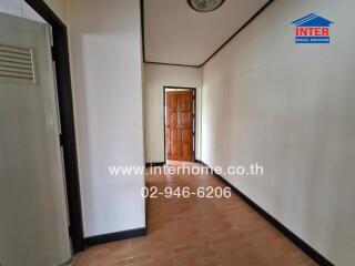 Hallway with tiled floor and wooden door at the end