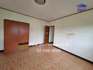 Empty bedroom with wooden wardrobe and tile flooring