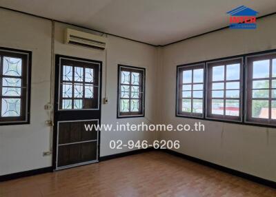 A room with windows, an air conditioner, and a door.